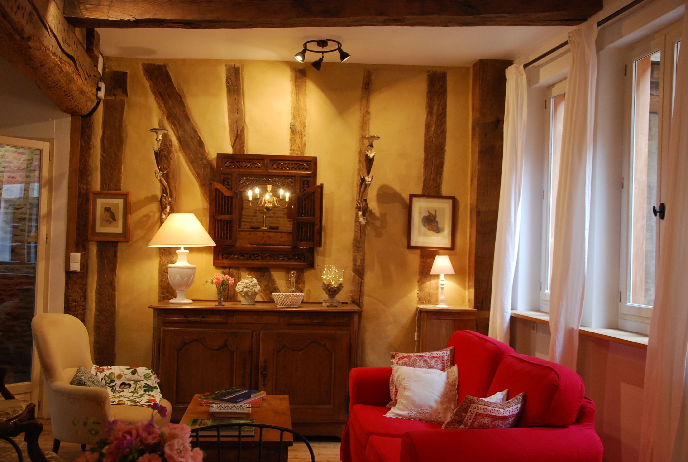 Una sala de estar acogedora con un sofá rojo, un aparador de madera y dos lámparas.