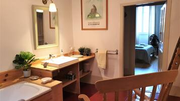 A bathroom with a wooden vanity, a sink, a mirror, and a towel rack.