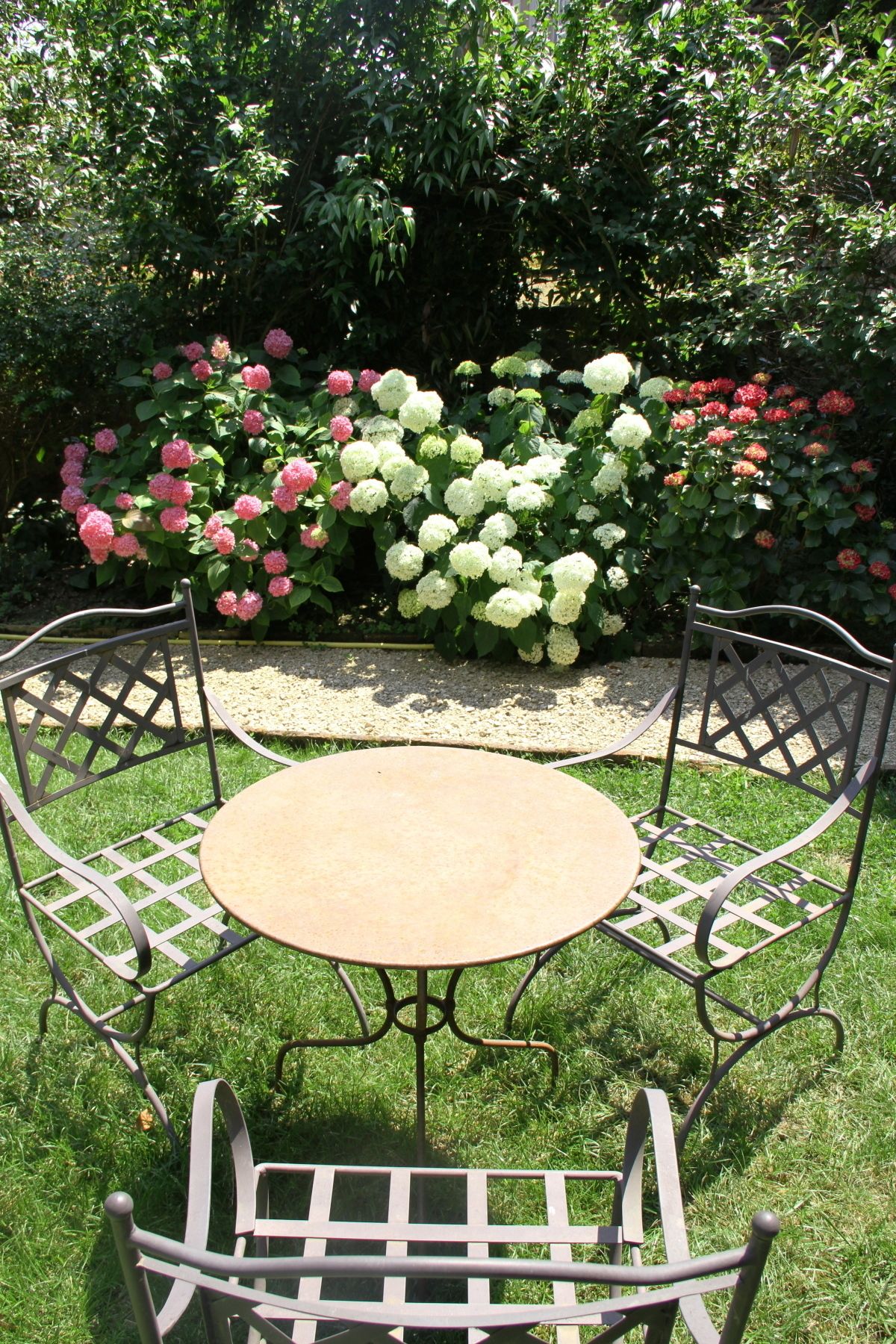 Una mesa redonda de metal con cuatro sillas en un jardín.