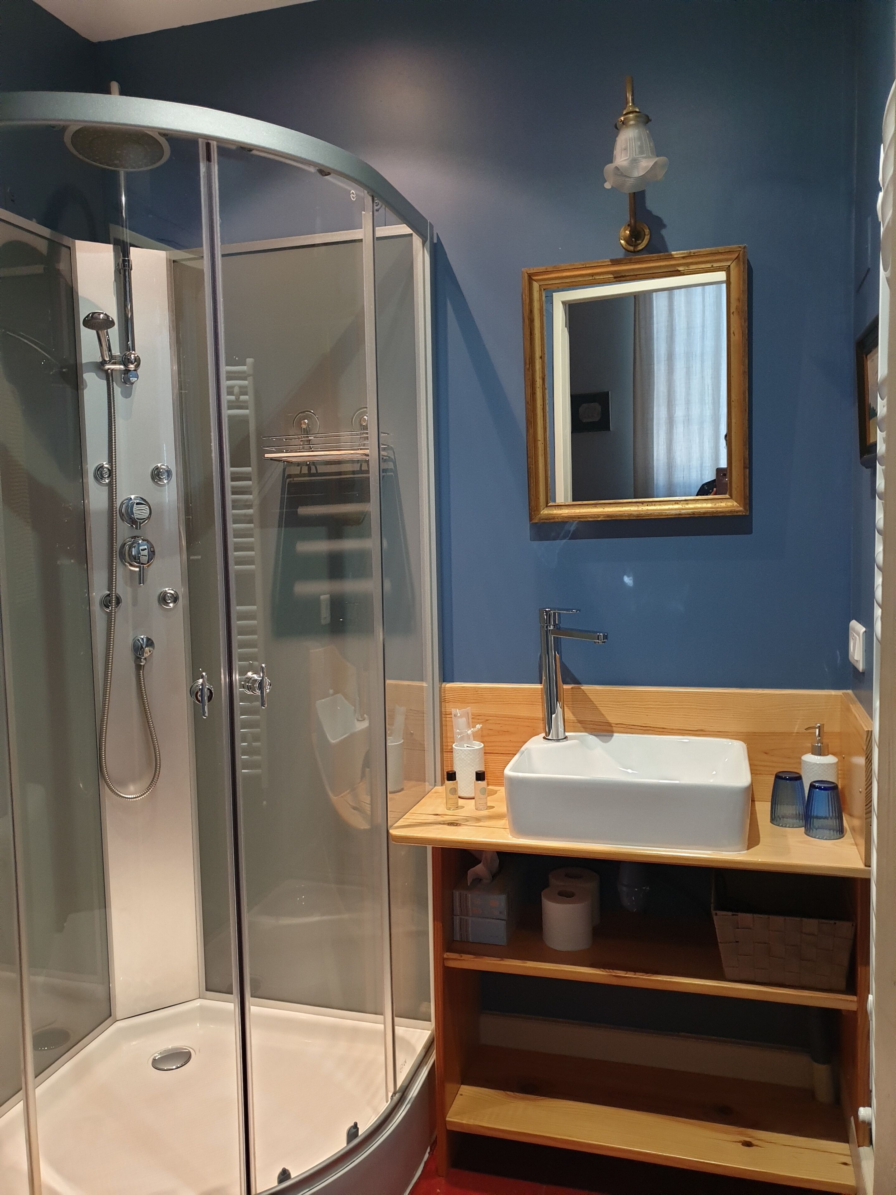 A modern bathroom with a glass-enclosed shower, a wooden vanity with a sink, and a mirror above it.