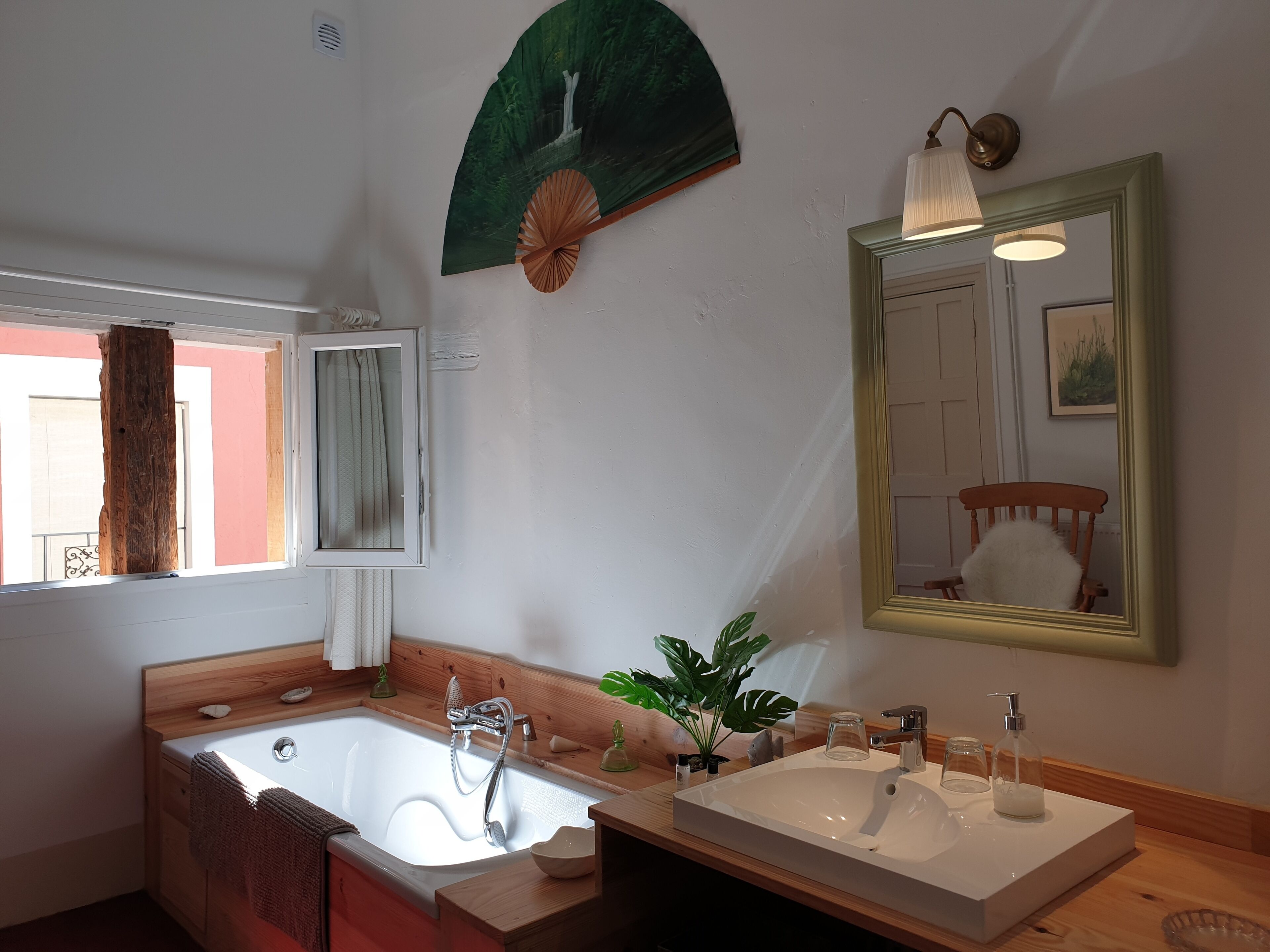 A modern bathroom with a freestanding bathtub, a large mirror, and a wooden vanity with a sink.