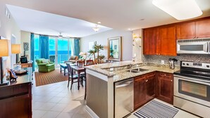 A modern kitchen with granite countertops, stainless steel appliances, and wooden cabinets. - Aqua Beach Resort by Aneliya's Rentals (Panama City Beach)