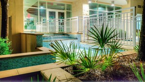 A pool area with a white fence, a hot tub, and a view of the building in the background. - Aqua Beach Resort by Aneliya's Rentals (Panama City Beach)