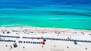 A beach with rows of blue chairs and umbrellas, a sandy beach, and the ocean. - Aqua Beach Resort by Aneliya's Rentals (Panama City Beach)