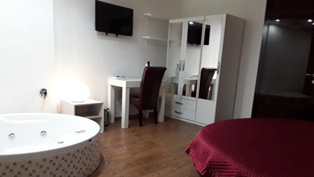 A bedroom with a large bed, a desk, a chair, a wardrobe, and a bathtub. - La Dimora dell'Architetto (Gravina in Puglia)