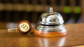 A hotel reception area with a wooden reception desk and a silver bell. - La Dimora dell'Architetto (Gravina in Puglia)