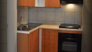 A compact kitchen with wooden cabinets, a stainless steel sink, and a built-in oven. - La Dimora dell'Architetto (Gravina in Puglia)