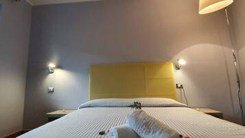 A hotel room with a bed, a headboard, bedside lamps, and a floor lamp.