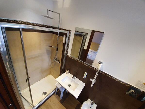 A bathroom with a glass-enclosed shower, a white sink, and a mirror.