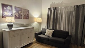 A living room with a sofa, a cabinet, and two wall-mounted lamps.