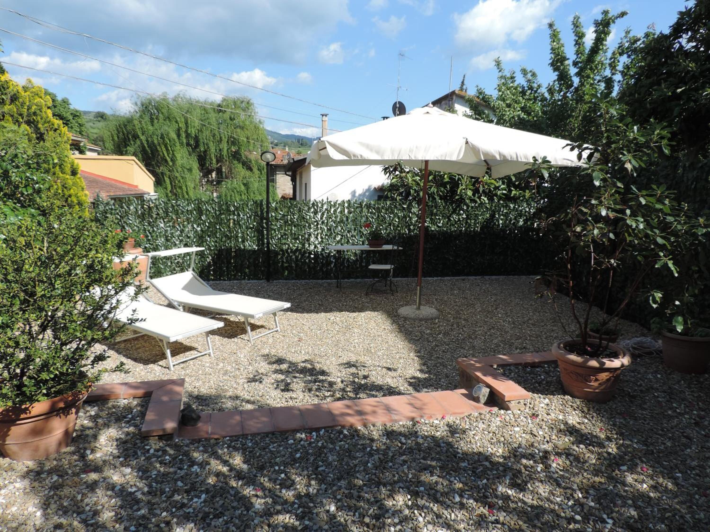 Un patio con mobiliario exterior, una mesa y un gran paraguas.