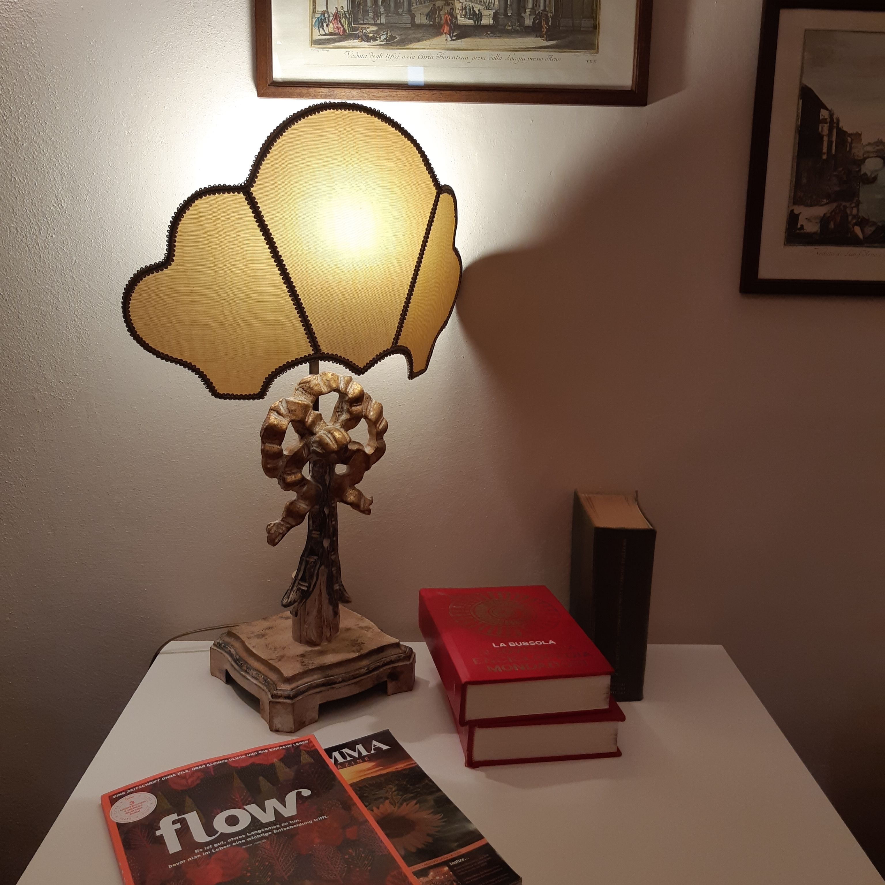 Une table avec une lampe, des livres et un tableau encadré accroché au mur.