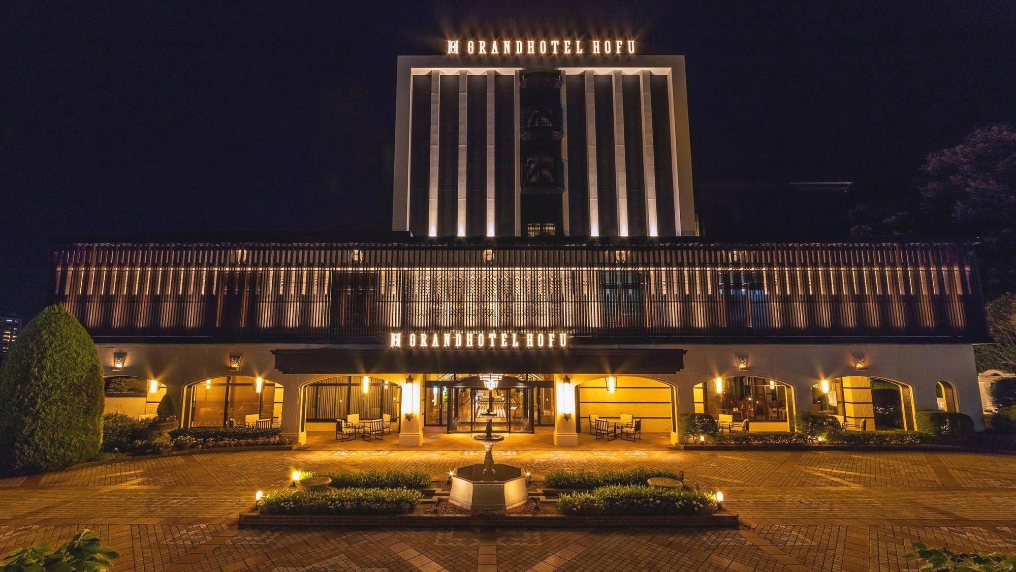 A hotel with a prominent entrance, a covered outdoor seating area, and a central water feature.