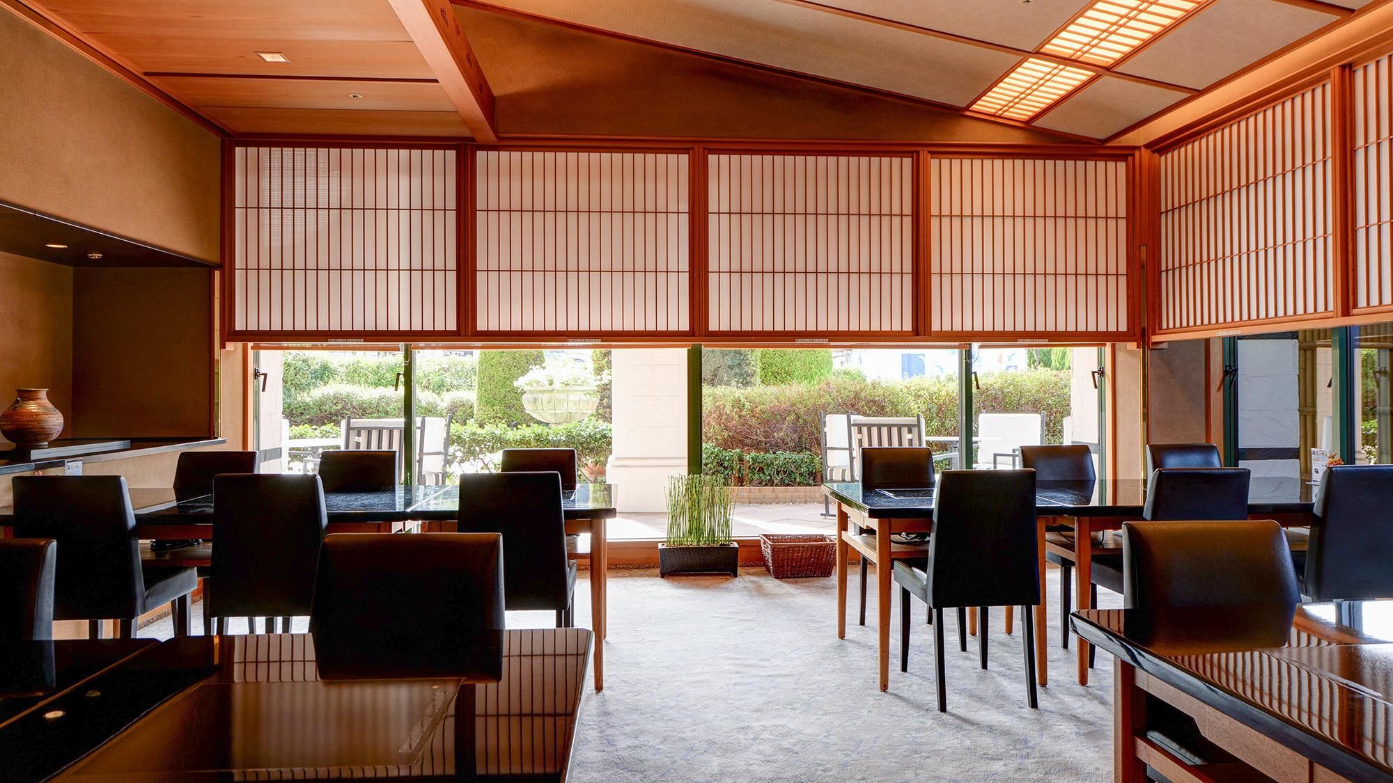 A traditional Japanese-style room with tatami flooring, low tables, and chairs.