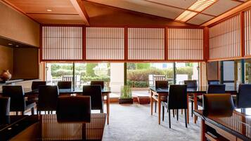A traditional Japanese-style room with tatami flooring, low tables, and chairs.