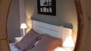 A bedroom with a bed, pillows, a nightstand, a lamp, and a framed picture on the wall. - Les Chaufourniers (Crouay)