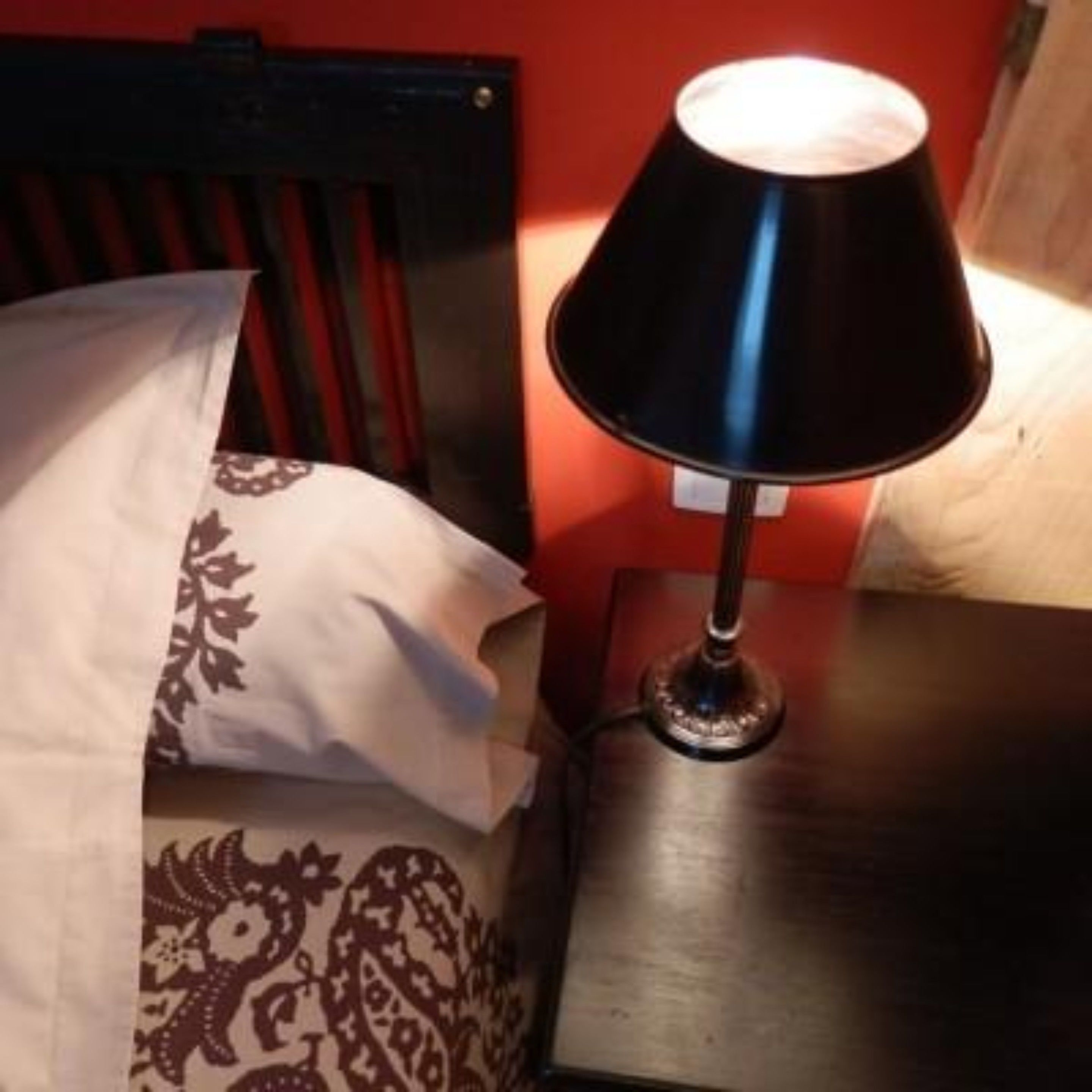 A bed with patterned pillows and a bedside table with a lamp.