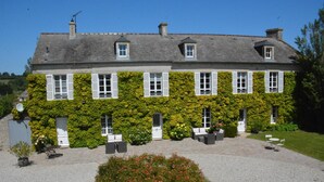 A two-story building with a garden patio area, outdoor seating, and a gravel driveway. - Les Chaufourniers (Crouay)