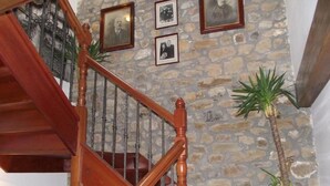 A wooden staircase with stone walls and framed photographs. - Posada Solar Montero de la Concha (Santa Maria de Cayon)