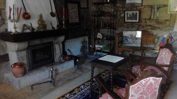 A cozy room with a fireplace, a table, and patterned chairs.