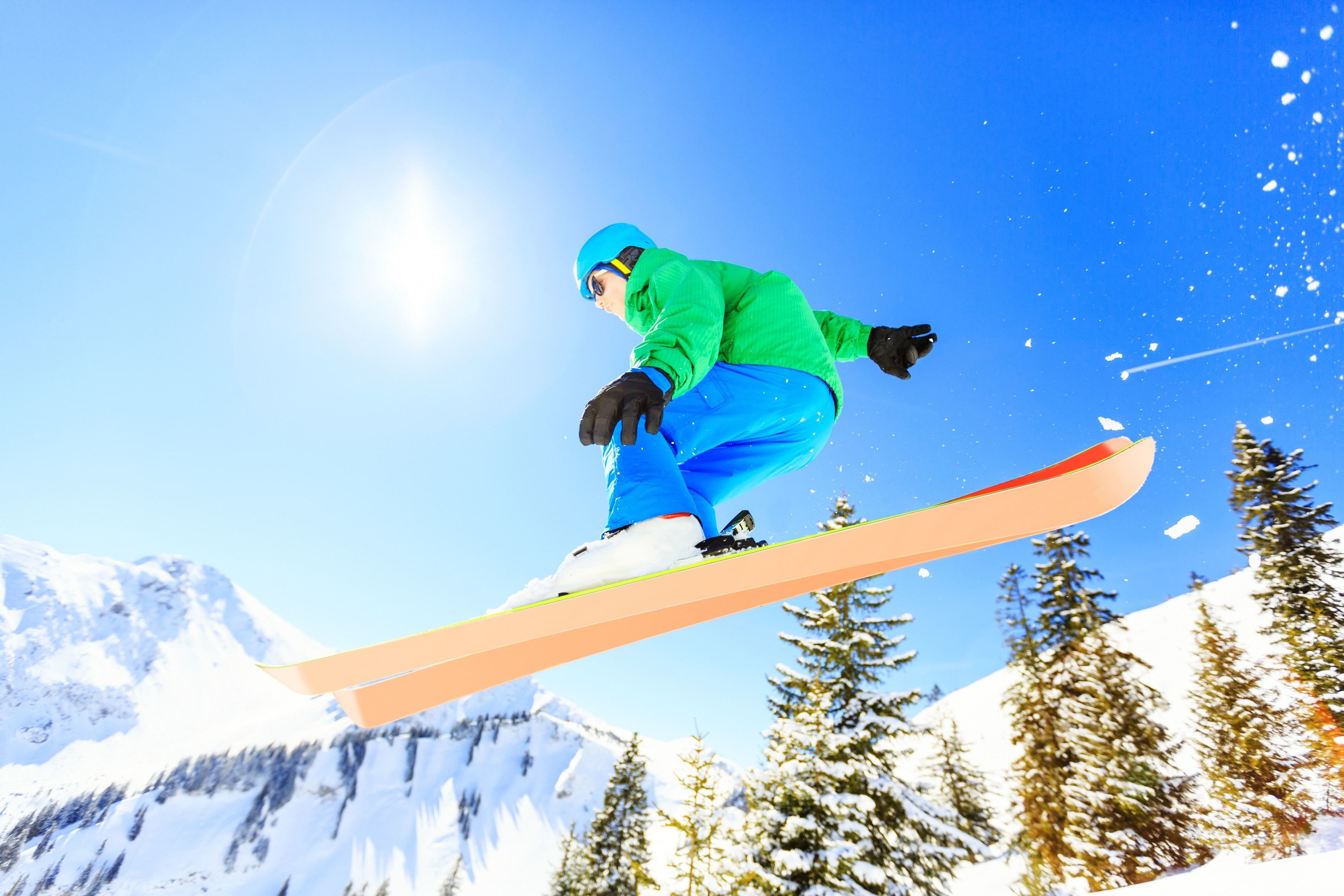 A snowboarder in mid-air against a snowy mountain backdrop.