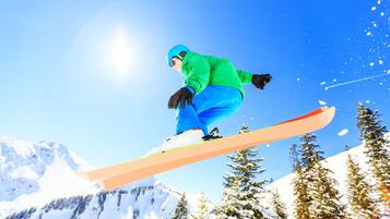 A snowboarder in mid-air against a snowy mountain backdrop.