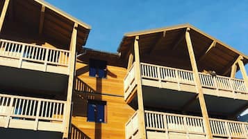 A wooden multi-story building with balconies and a flat roof.