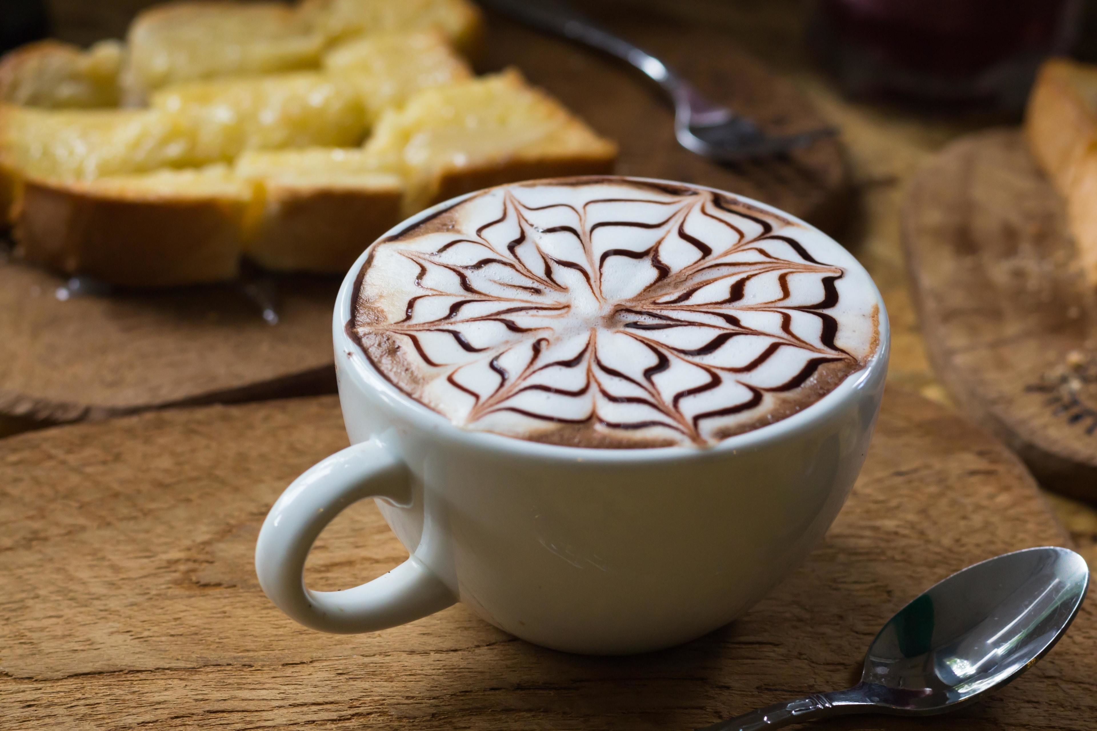 A cup of coffee with latte art on a wooden table.