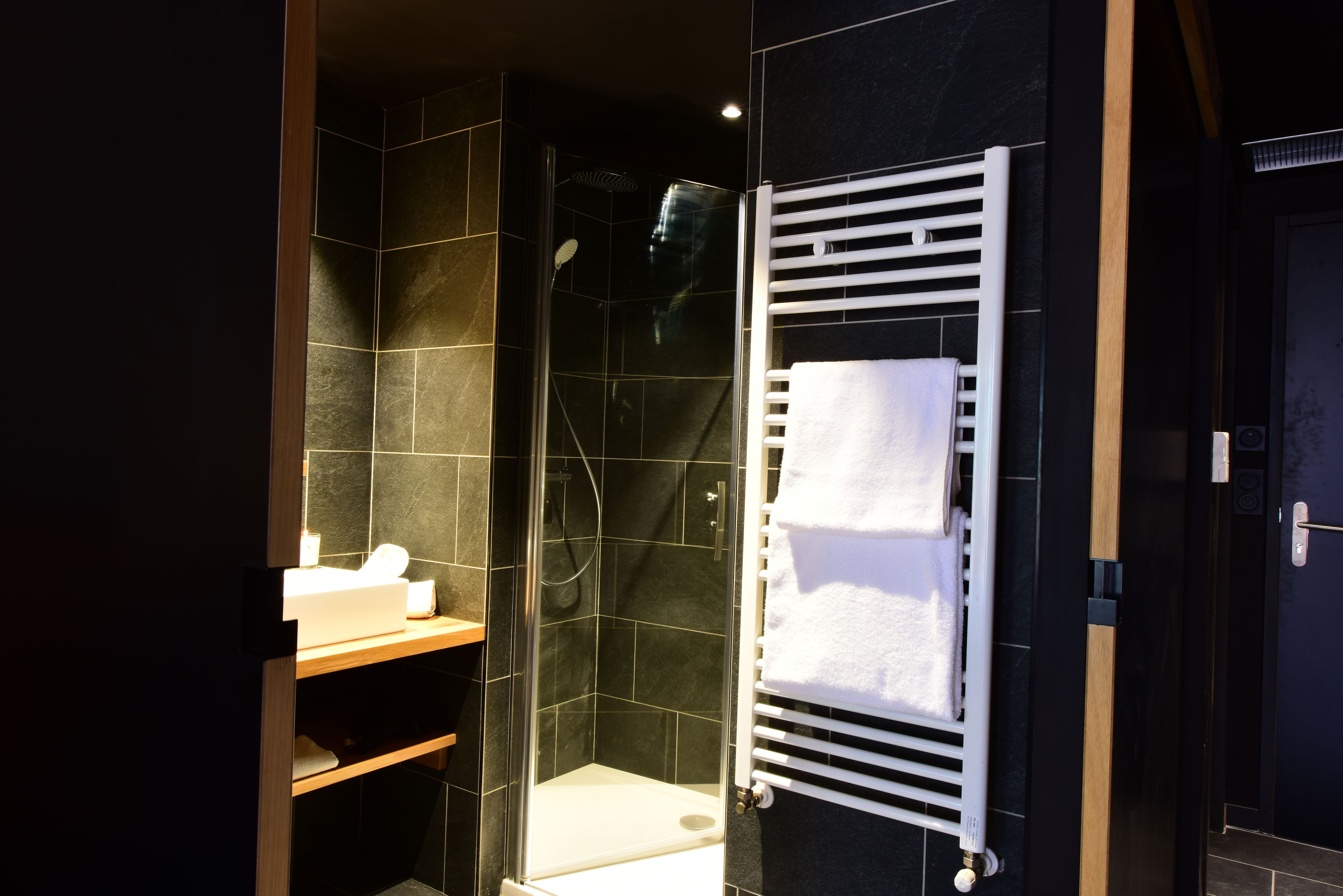 A modern bathroom with a glass-enclosed shower, a white towel rack, and a wooden vanity.