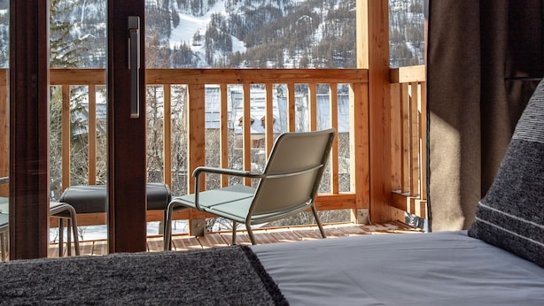 Un balcón con vistas a montañas nevadas y una silla.
