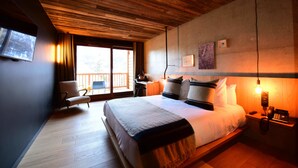 Un dormitorio moderno con una cama grande, techo de madera, un escritorio y una silla.