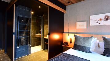 Een moderne hotelkamer met een groot bed, een inloopkast en een douche.