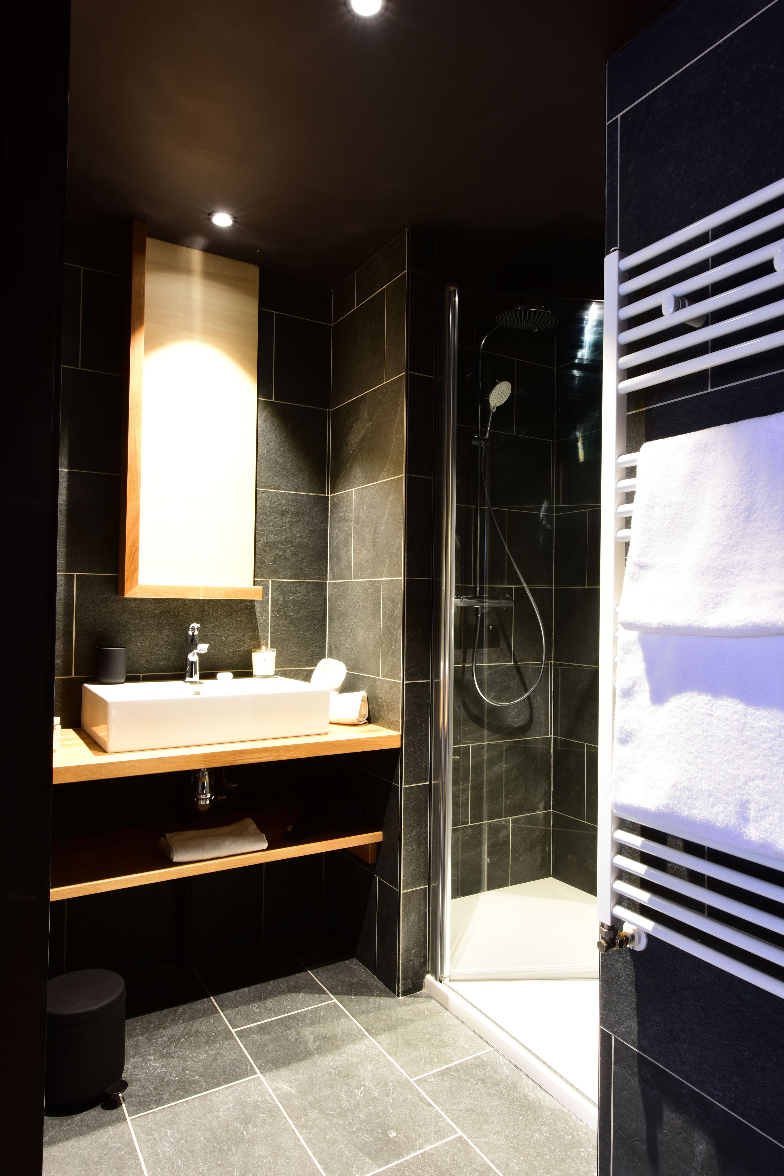 Ein modernes Badezimmer mit großem Spiegel, Waschbecken und Duschbereich.