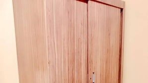 Une armoire en bois dotée d’une porte coulissante, placée contre un mur uni.