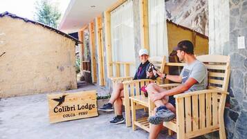 Two people seated on wooden chairs outside a lodge named 'Colibri Lodge' in Colca, Peru.