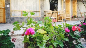 A garden with pink flowers and a wooden outdoor seating area. - Colibrí Lodge (Tapay)