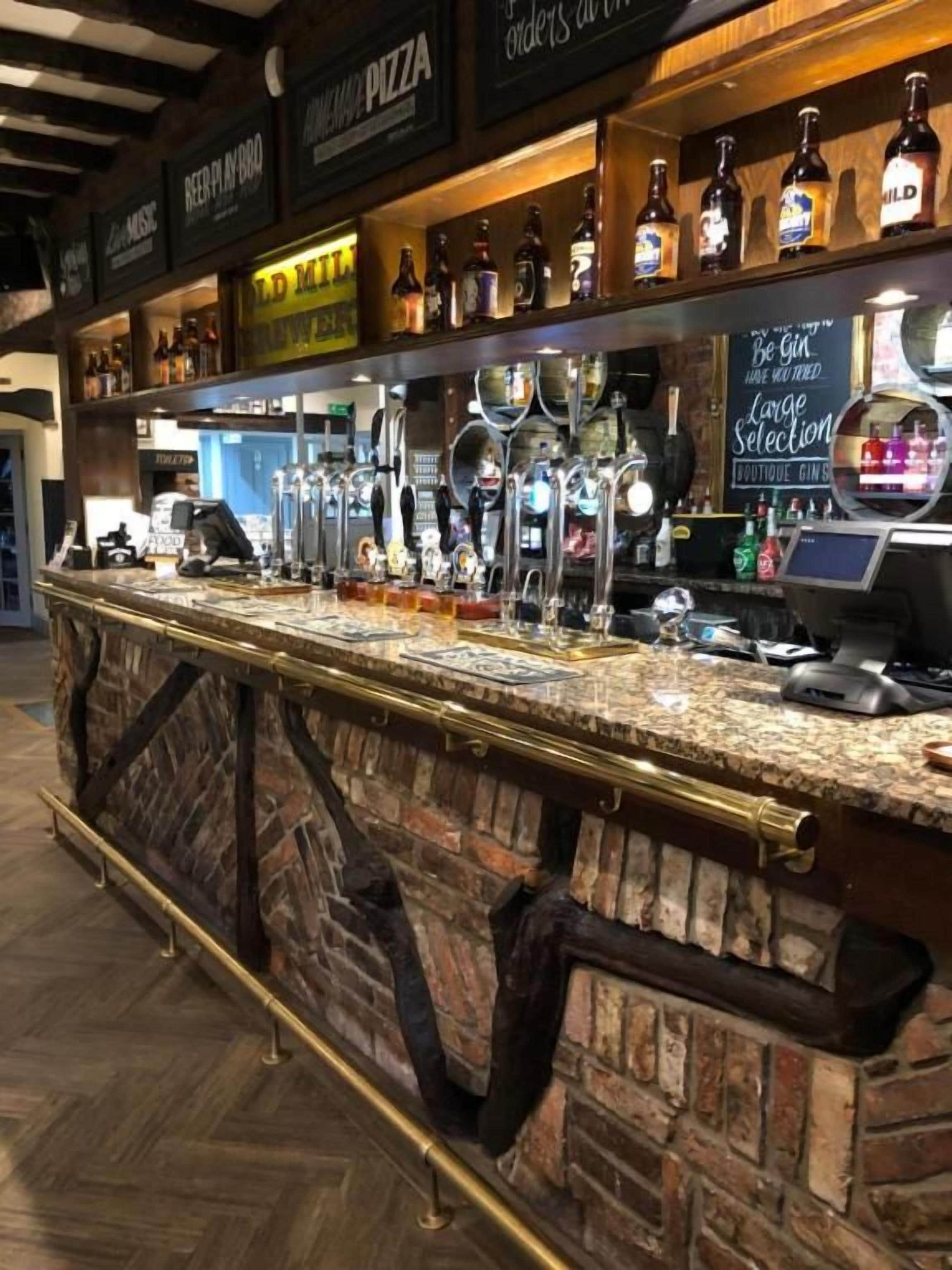 Een bar met een stenen toonbank, meerdere bierkraaninstallaties en een keuze uit flessen.