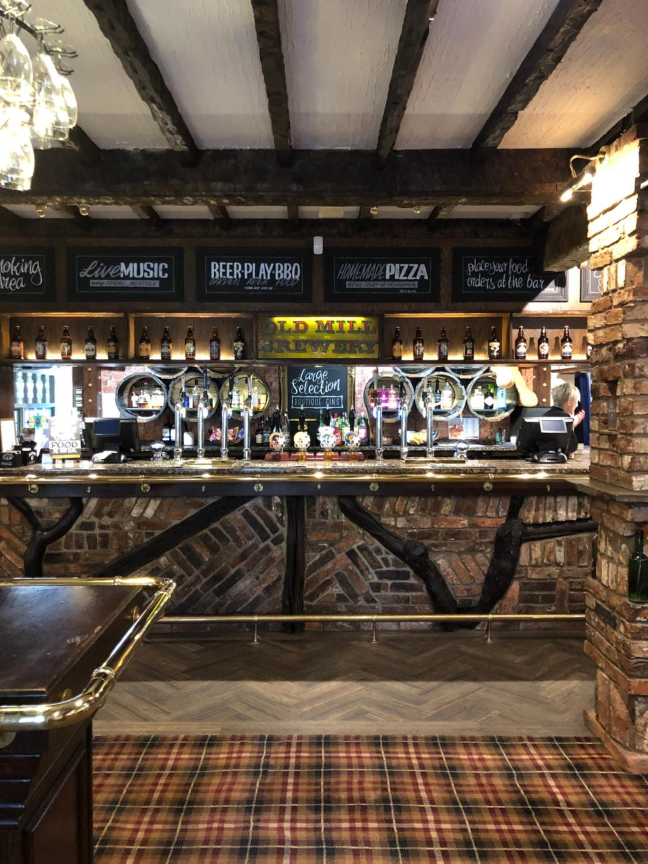 A bar area with a selection of beers, a sign for live music, and a place to order food at the bar.