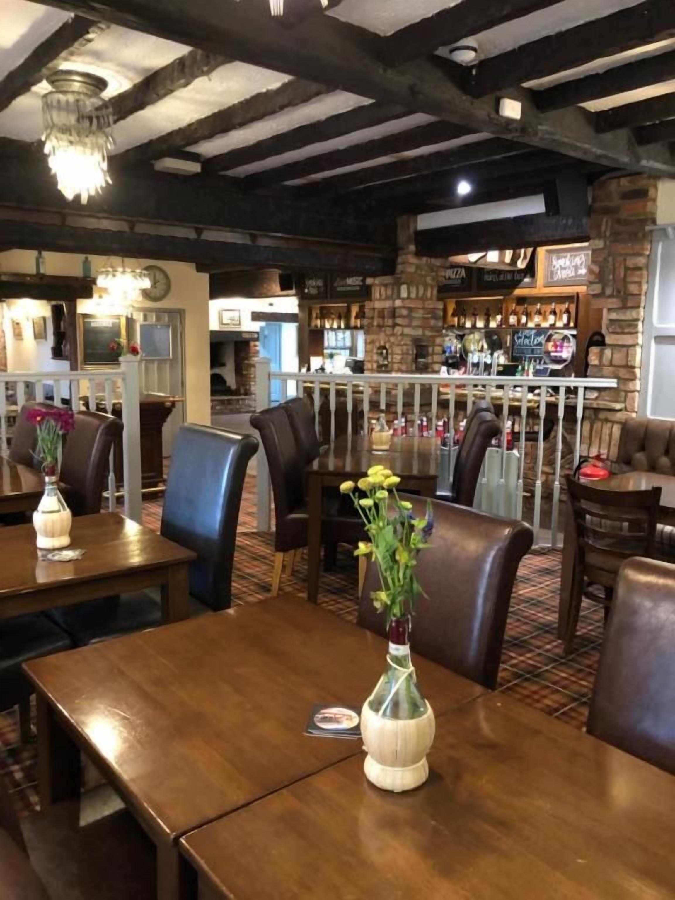A restaurant with wooden tables, chairs, and a bar area.