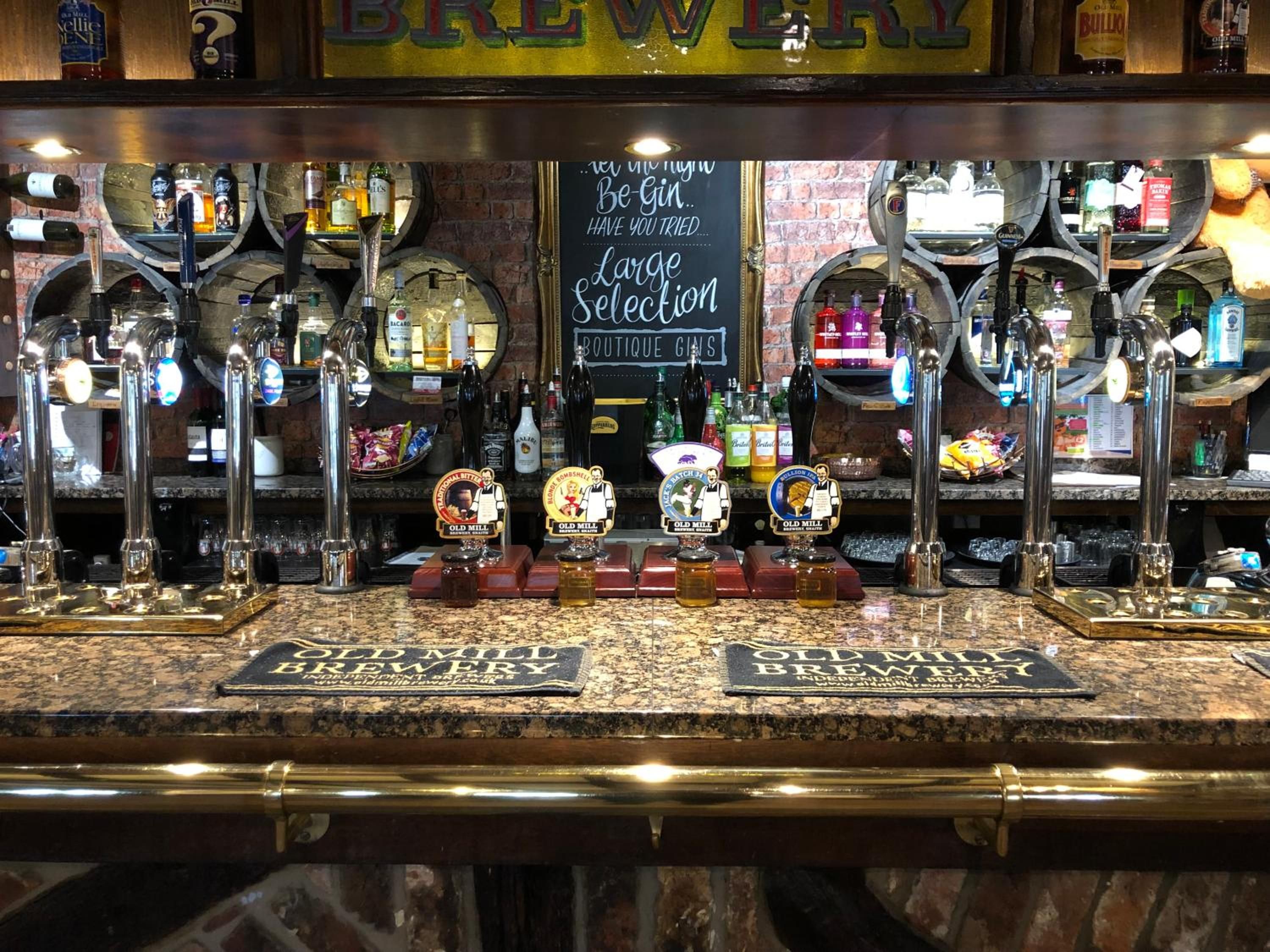 A bar with multiple taps and a sign indicating a large selection of boutique gin.