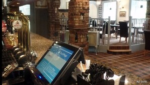 Eine Bar mit einem digitalen Touchscreen, einem Zapfhahn und einer Ziegelstütze.