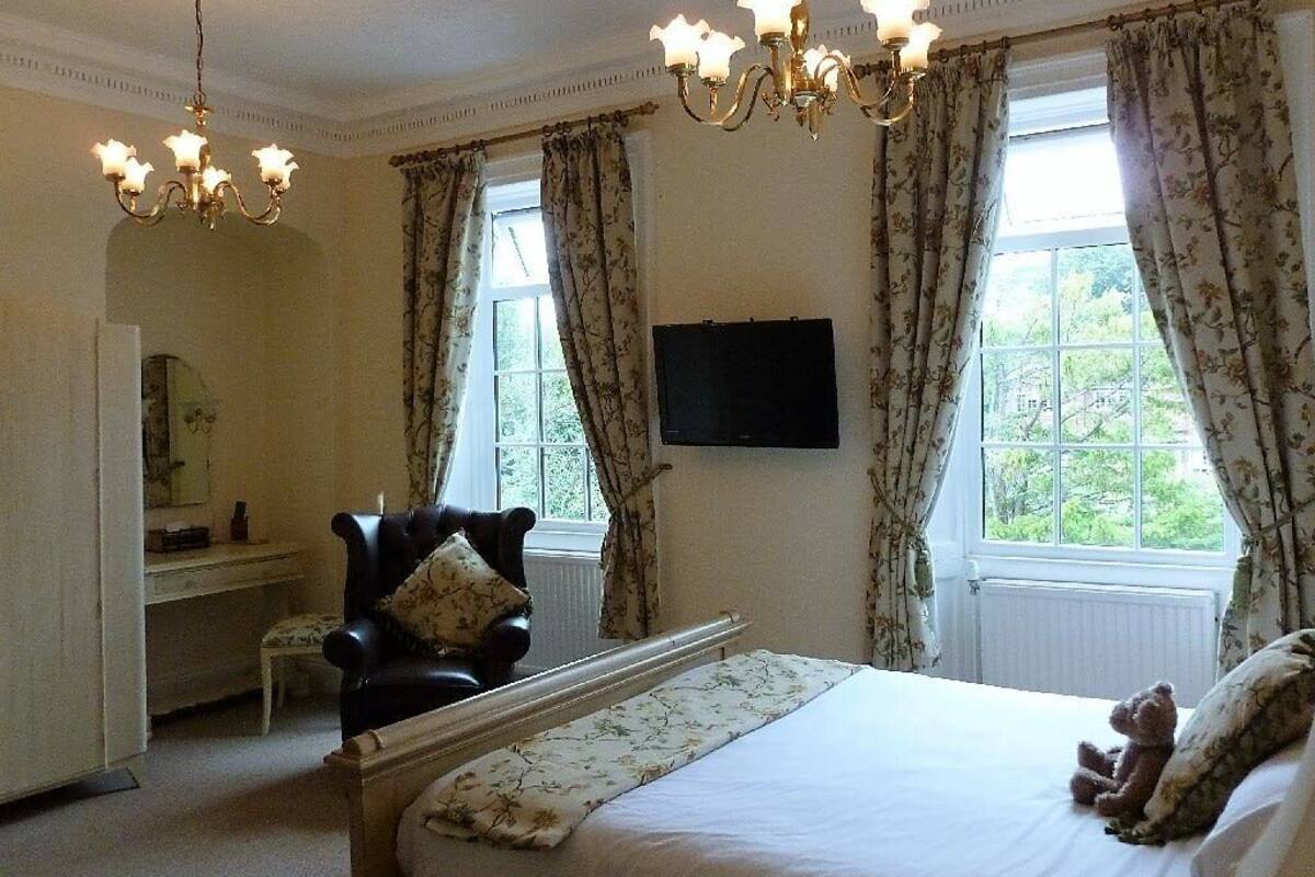 A bedroom with a bed, a chair, a desk, and a television.