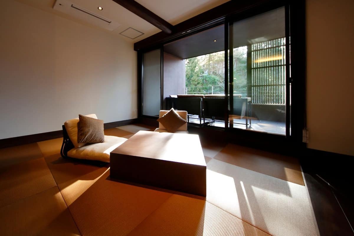 A minimalist room with tatami flooring, a low table, and a sofa with cushions.