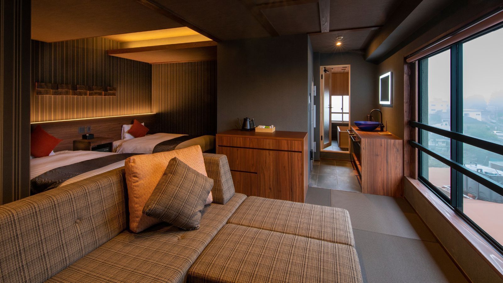 A modern interior with a sofa, wooden cabinets, and a view through large windows.