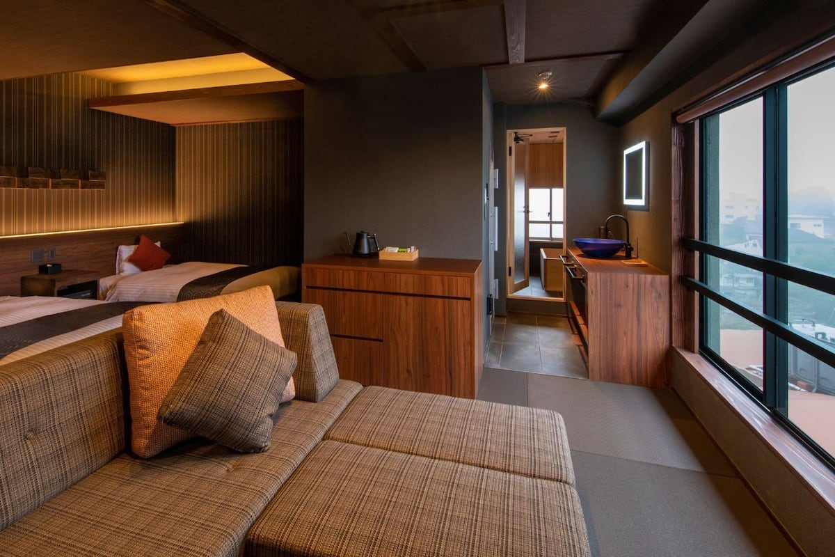 A modern interior with a sofa, wooden cabinets, and a view through large windows.