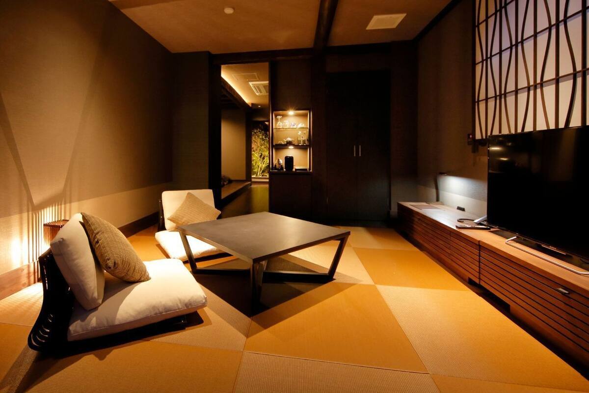 A modern hotel room with a sofa, a small table, a TV, and a cabinet.