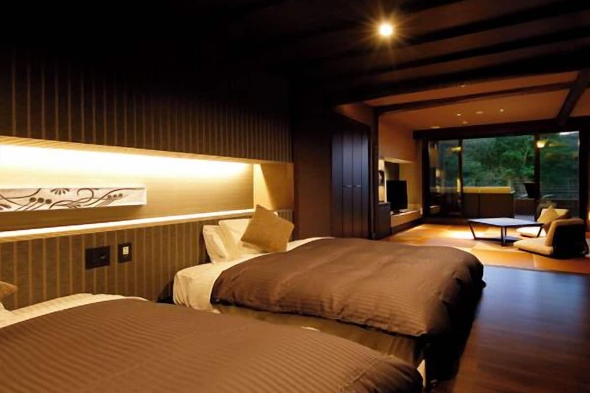 A modern hotel room with two beds, a large window, and a view of the outdoors.