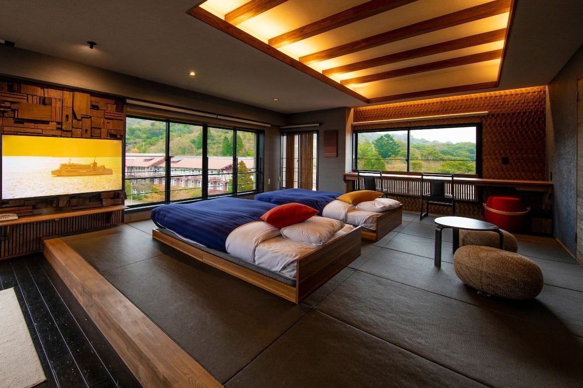 A modern bedroom with a large bed, a TV, and a view of the outdoors.