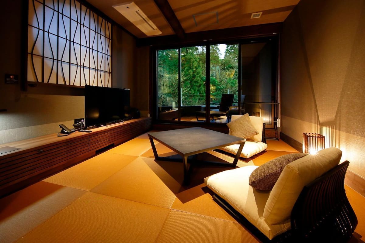 A modern interior with tatami flooring, a sofa, a coffee table, and a TV on a wooden console.