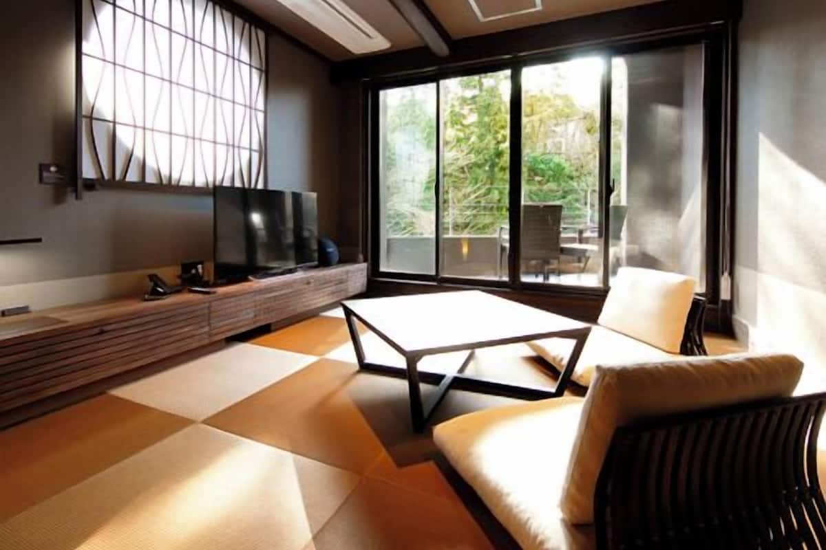 A modern living room with a sofa, a coffee table, a TV, and a large window.